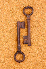Two antique keys on cork background