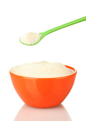 A colorful bowl full of white sugar with bright spoon