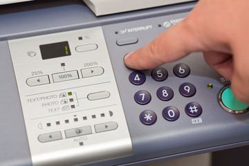 finger pressing the buttons of the copier