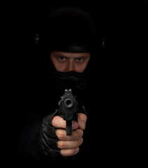 Armed assassin with motorcycle helmet aiming into the camera