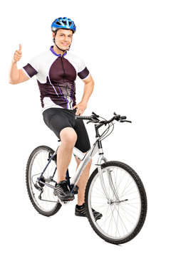 Smiling bicyclist posing on a bicycle and giving a thumb up