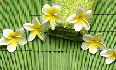 Fototapeta na wymiar frangipani flower and green towel on straw mat