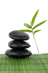 Fototapeta na wymiar zen stones and a fresh bamboo leaf on green mat
