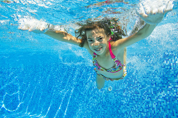 Happy smiling underwater child in swimming pool, summer vacation