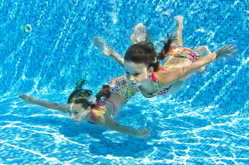 Happy smiling underwater children in swimming pool on vacation