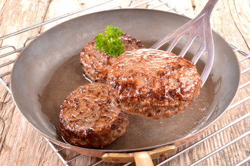 fried hamburger meat in a copper pan