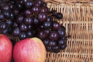 Apples and grapes in  wicker basket.