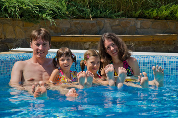 Happy family with  two kids in swimming pool. Summer vacation