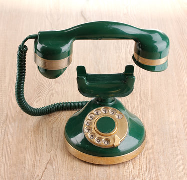 Retro phone with floating handset on wooden background