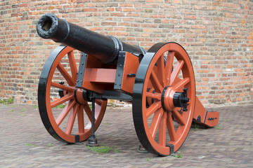 Old medieval artillery canon before a brick wall