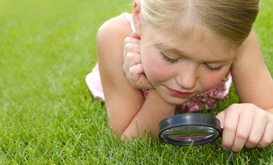 girl looking through magnifying glass outdoors
