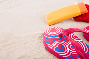 Flipflops ,sunscreen,towel on sand beach