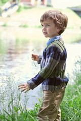 Elegant boy stands on  banks of River