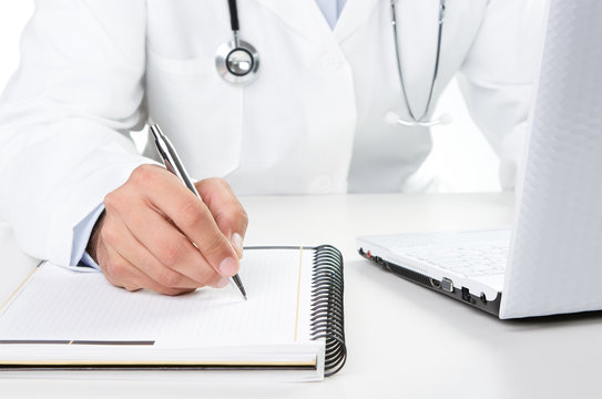 Doctor at work writing notes by the desk