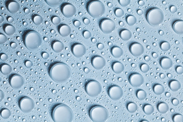 Voluminous water drops on a blue and smooth surface