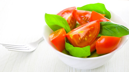 Fresh tomatoes with basil leaves in a bowl