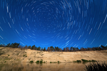 stars around the Pole Star in the background of the river