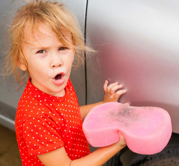 a little girl washing the car with a sponge 