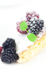 cake with icing, raspberry, blackberry and mint  on a white back
