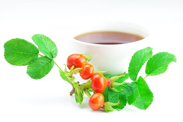 cup of tea and rosehip berries with leaves on white background