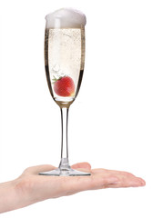 Woman hand offering glass of champagne with strawberry