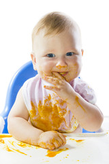 A young blue-eyed child feeding pumpkin puree