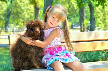Little girl hugging a poodle dog