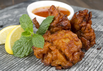 Onion Bhajis & chili sauce, lemon & mint leaves on a slate