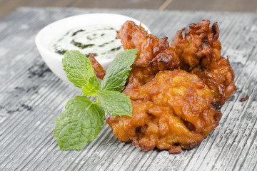 Onion Bhajis,  mint and yoghurt raita & mint leaves on a slate