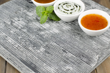 Slate with chili sauce, mint raita, mango chutney & mint leaves