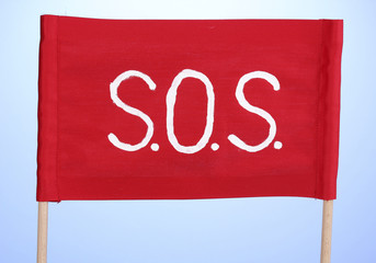 SOS signal written on red cloth on blue background