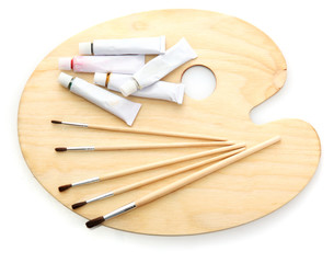 wooden art palette, tubes with paint and brushes isolated
