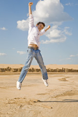 Young man jumping in the air against a blue sky