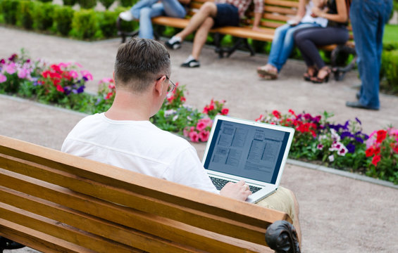 Man using a laptop in a public park