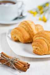 Croissants with cup of tea and cinnamon