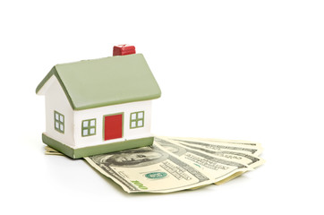 Model of a house lying on some banknotes
