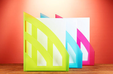 Colorful trays for papers on red background close-up