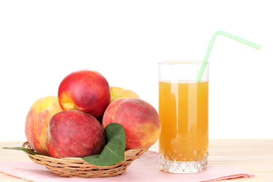 Ripe peaches and juice on wooden table on white background