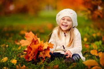 preschool little girl with autumn leaves in the park