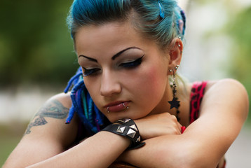 Portrait of beautiful diverse female with dyed blue hair and tattoo. Inclusive model with unique...