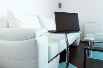 Modern living room with white leather sofa and laptop