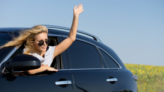 Woman Leaning From Car Window Waving