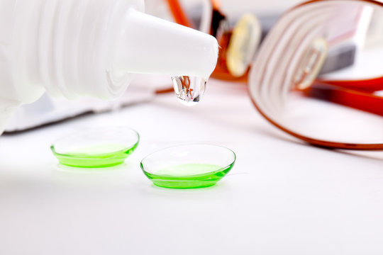 Close-up of green contact lenses in container with solution.