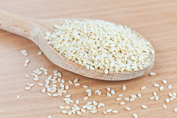 Wooden spoon filled with sesame seeds on the kitchen board