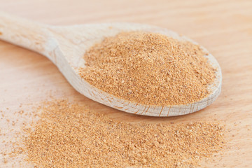 Wooden spoon filled with grated nutmeg on the kitchen board
