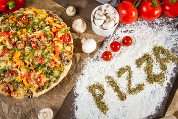 The words 'pizza' written on the flour with spices oregano