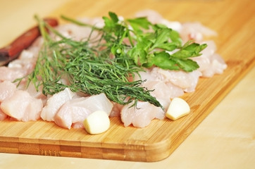 Cutted chicken fillet with parsley ang garlic and a knife