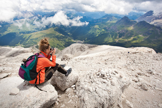 cute girl taking pictures of beautiful panorama in the alps