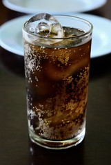 Cola into a glass with ice cubes