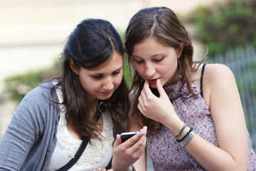 Two girlfriends in park with a mobile phone